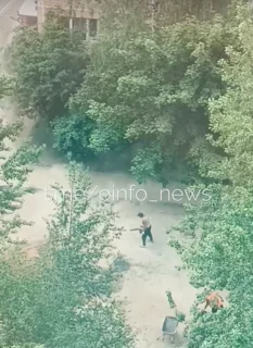 Дворник с воздуходувкой поднимает пыль во дворе домов в посёлке ВНИИССОК